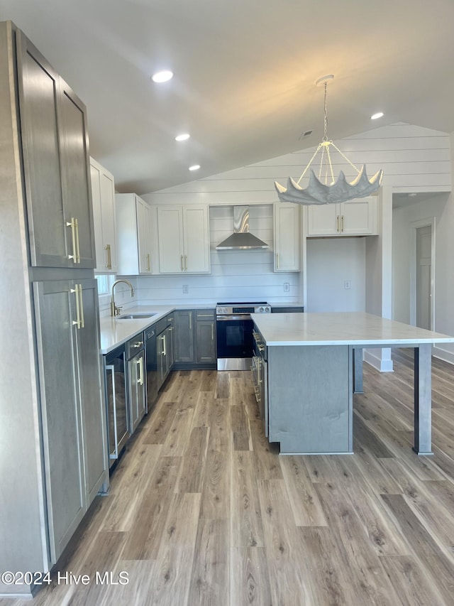 kitchen featuring pendant lighting, wall chimney range hood, sink, vaulted ceiling, and stainless steel electric range oven