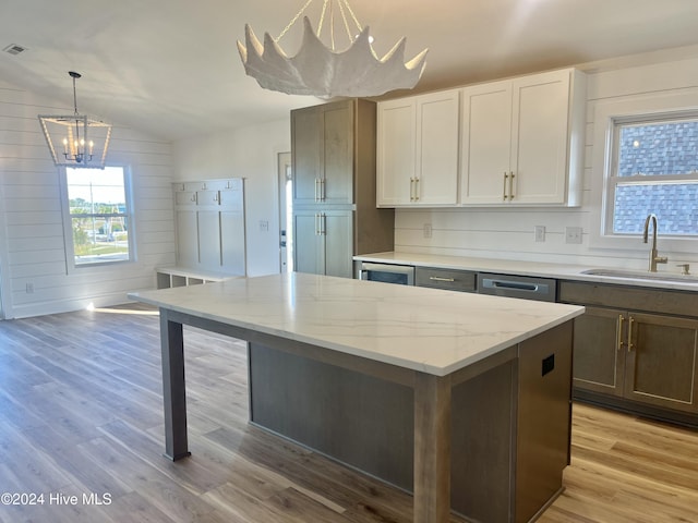 kitchen featuring white cabinetry, wood walls, lofted ceiling, and light wood-type flooring