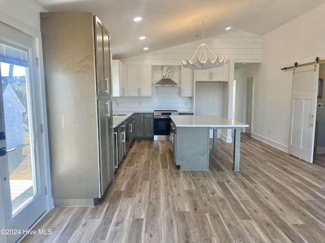 kitchen with electric stove, plenty of natural light, wall chimney exhaust hood, and a barn door