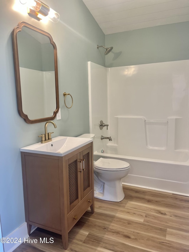 full bathroom with vanity, shower / tub combination, vaulted ceiling, toilet, and wood-type flooring