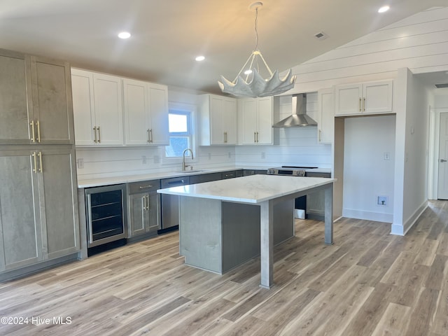 kitchen featuring wall chimney exhaust hood, beverage cooler, pendant lighting, a kitchen island, and lofted ceiling