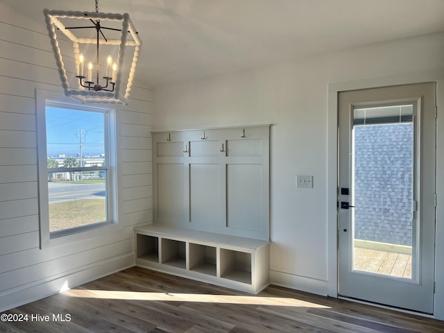 mudroom featuring a chandelier, wooden walls, and dark wood-type flooring