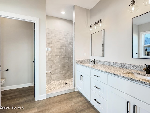 bathroom featuring a tile shower, vanity, hardwood / wood-style flooring, and toilet