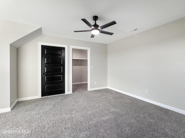 unfurnished bedroom with a spacious closet, ceiling fan, carpet floors, and a closet