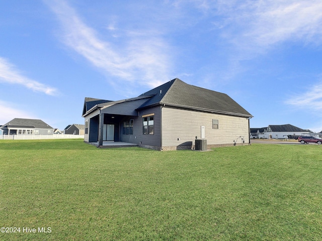 rear view of property with cooling unit, a patio area, and a lawn