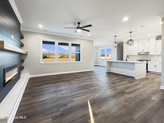 unfurnished living room featuring ceiling fan, dark hardwood / wood-style flooring, sink, and ornamental molding