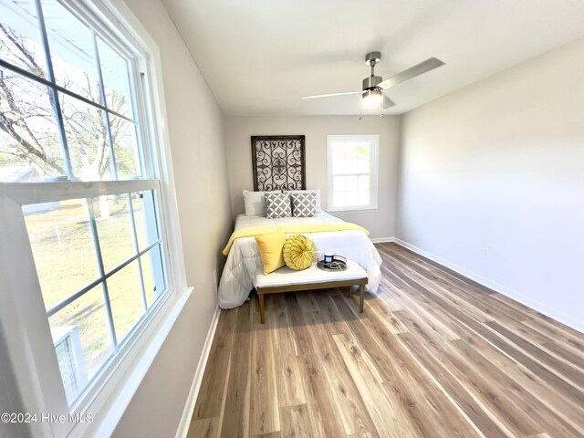 bedroom featuring light wood-type flooring, multiple windows, and ceiling fan