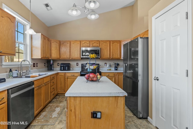 kitchen with lofted ceiling, sink, hanging light fixtures, a kitchen island, and black appliances