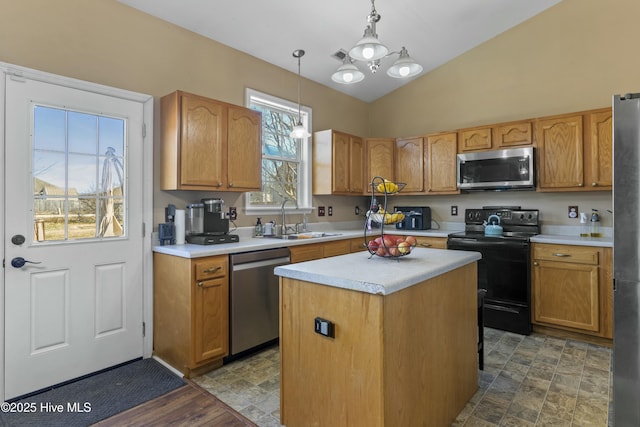 kitchen featuring vaulted ceiling, appliances with stainless steel finishes, decorative light fixtures, sink, and a center island