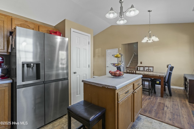 kitchen with lofted ceiling, a chandelier, hanging light fixtures, a center island, and stainless steel fridge with ice dispenser