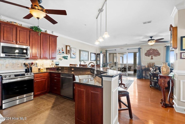 kitchen with sink, kitchen peninsula, stainless steel appliances, and a breakfast bar area