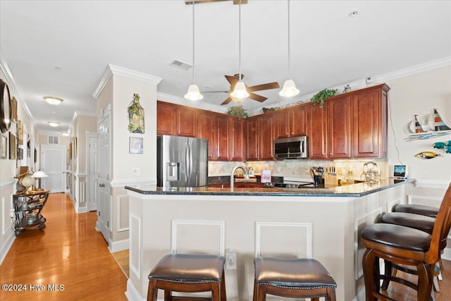 kitchen with a kitchen breakfast bar, crown molding, hanging light fixtures, and stainless steel appliances