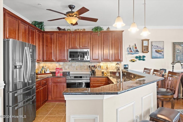 kitchen with stainless steel appliances, dark stone countertops, crown molding, decorative light fixtures, and a breakfast bar