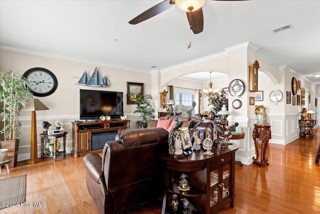 living room with ceiling fan with notable chandelier, crown molding, and light hardwood / wood-style flooring