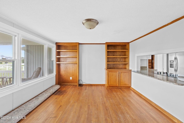 unfurnished living room featuring a textured ceiling, light wood-type flooring, and crown molding