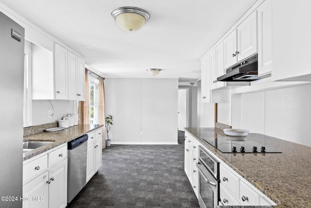 kitchen with white cabinets, stainless steel appliances, stone counters, and a textured ceiling