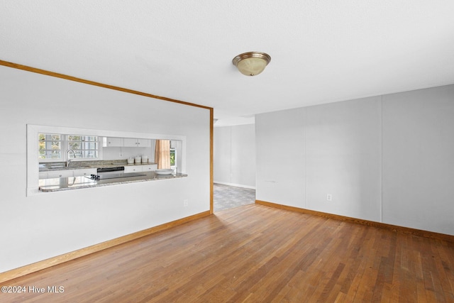 unfurnished living room featuring hardwood / wood-style floors and ornamental molding