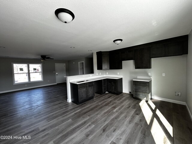 unfurnished living room with a textured ceiling, ceiling fan, and dark wood-type flooring