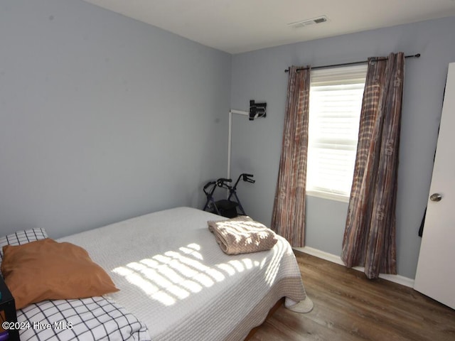 bedroom with dark hardwood / wood-style flooring and multiple windows