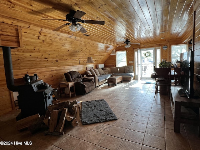 tiled living room featuring wood ceiling, wooden walls, vaulted ceiling, and a wood stove