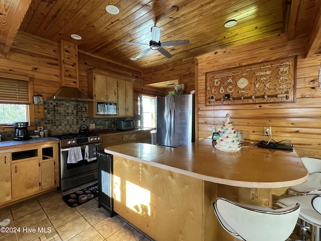 kitchen with light tile patterned flooring, wood walls, wooden ceiling, and appliances with stainless steel finishes