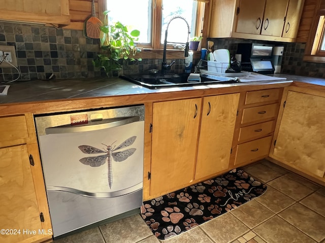 kitchen featuring tasteful backsplash, dishwasher, sink, tile patterned flooring, and tile counters