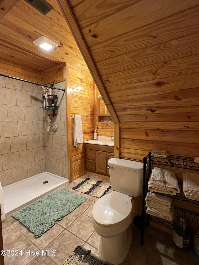 bathroom featuring wood ceiling, wooden walls, tiled shower, vanity, and toilet