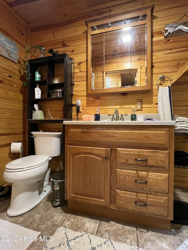 bathroom featuring vanity, wooden walls, and toilet