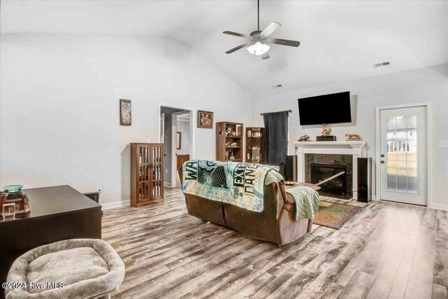 living room featuring light wood-type flooring, high vaulted ceiling, ceiling fan, and a premium fireplace