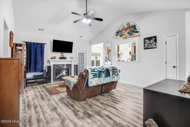 living room featuring ceiling fan, a fireplace, light hardwood / wood-style floors, and vaulted ceiling