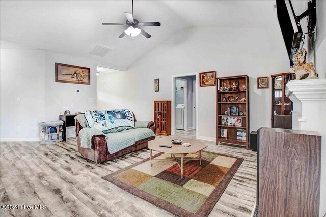 living room with ceiling fan, light hardwood / wood-style floors, lofted ceiling, and a fireplace