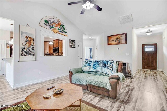 living room featuring ceiling fan, lofted ceiling, and light wood-type flooring