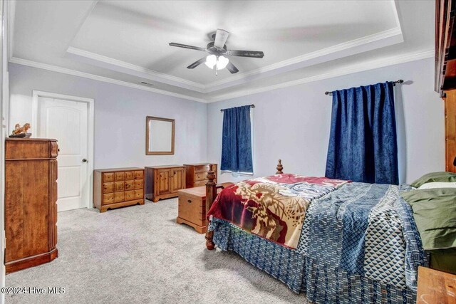 carpeted bedroom featuring ceiling fan, a raised ceiling, and ornamental molding