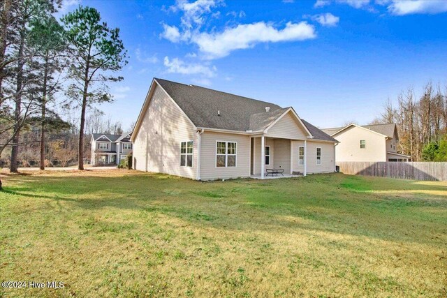 rear view of property featuring a lawn and a patio area