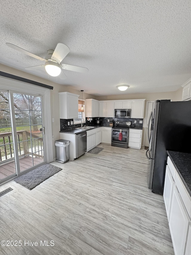 kitchen with sink, decorative light fixtures, appliances with stainless steel finishes, decorative backsplash, and white cabinets