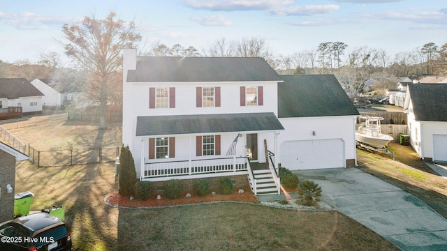 view of property featuring a porch, a garage, and a front yard