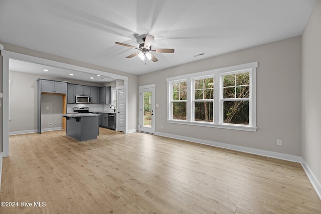 unfurnished living room with light hardwood / wood-style floors, ceiling fan, and sink