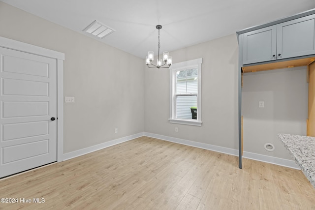 unfurnished dining area with light hardwood / wood-style flooring and a notable chandelier