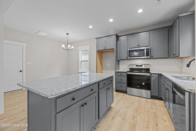 kitchen featuring gray cabinetry, a center island, pendant lighting, light hardwood / wood-style floors, and appliances with stainless steel finishes