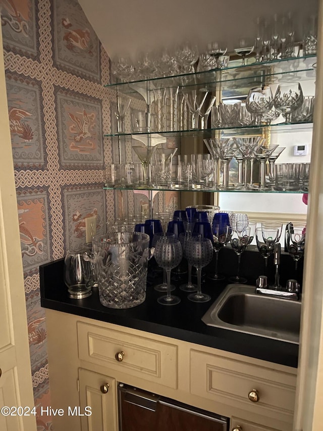 bar with cream cabinetry and sink