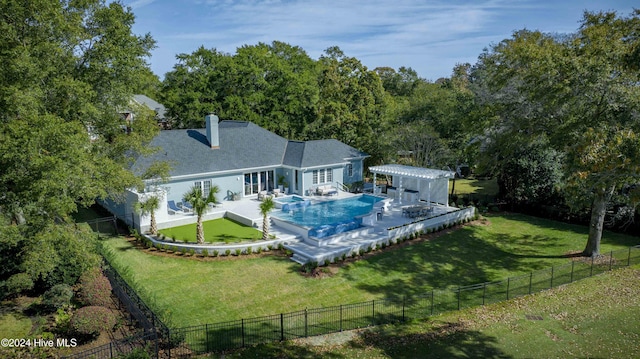 rear view of property featuring a patio, a lawn, an outdoor structure, and a fenced in pool