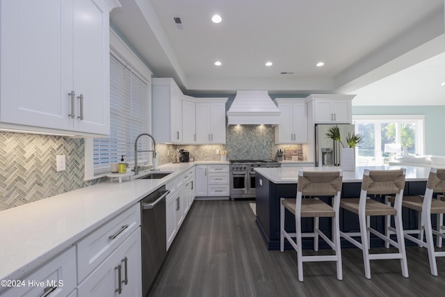 kitchen featuring tasteful backsplash, stainless steel appliances, custom range hood, sink, and white cabinetry