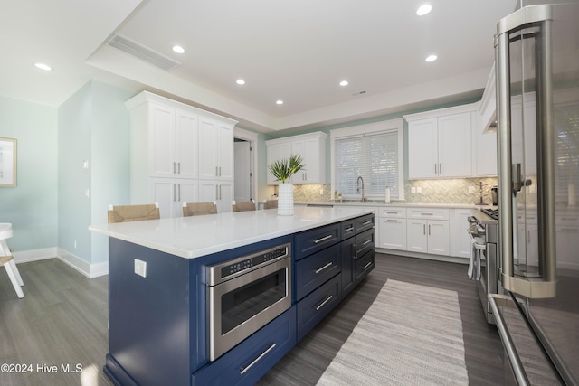 kitchen featuring tasteful backsplash, high quality appliances, a center island, sink, and white cabinetry