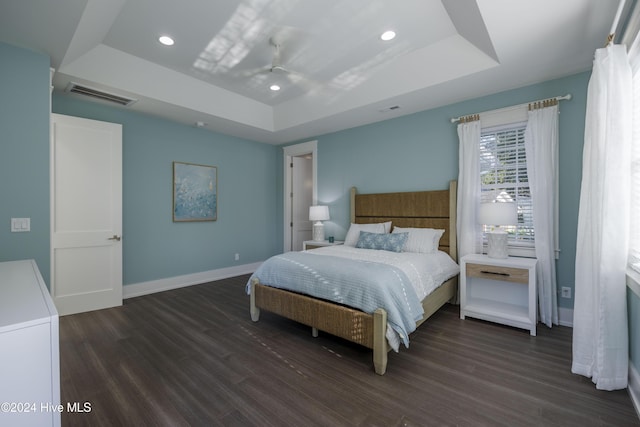 bedroom with ceiling fan, a raised ceiling, and dark hardwood / wood-style floors