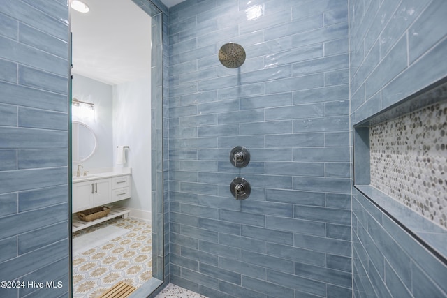 bathroom with a tile shower and vanity