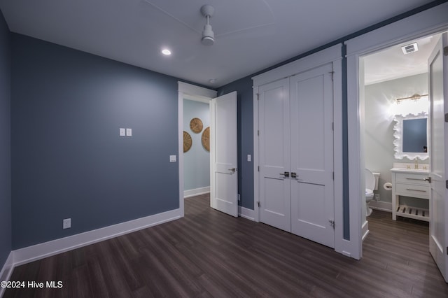 unfurnished bedroom featuring ensuite bathroom, a closet, and dark wood-type flooring