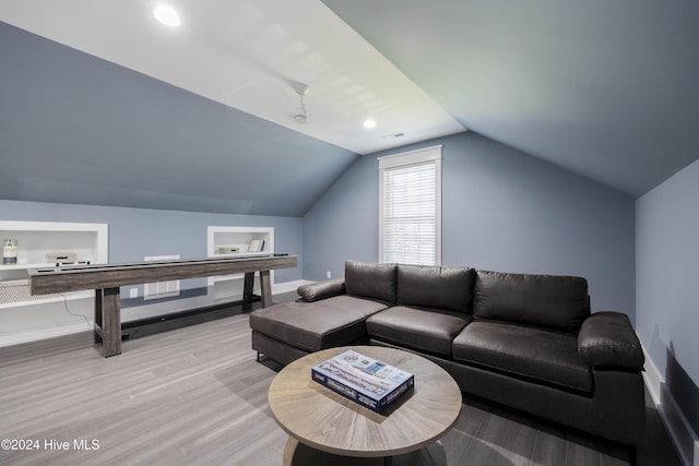 living room with ceiling fan, light hardwood / wood-style floors, and vaulted ceiling