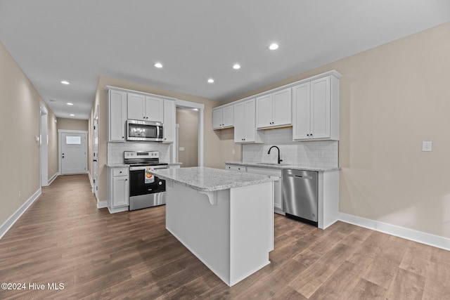 kitchen with appliances with stainless steel finishes, dark hardwood / wood-style flooring, a center island, and white cabinetry