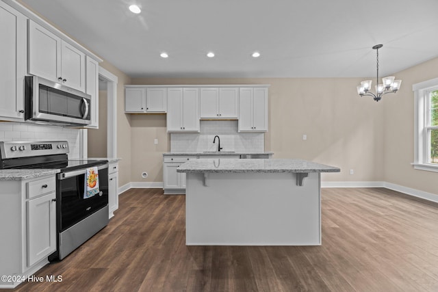 kitchen featuring appliances with stainless steel finishes, dark hardwood / wood-style floors, white cabinetry, and a kitchen island