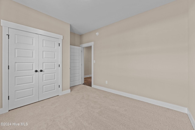 unfurnished bedroom featuring light colored carpet and a closet